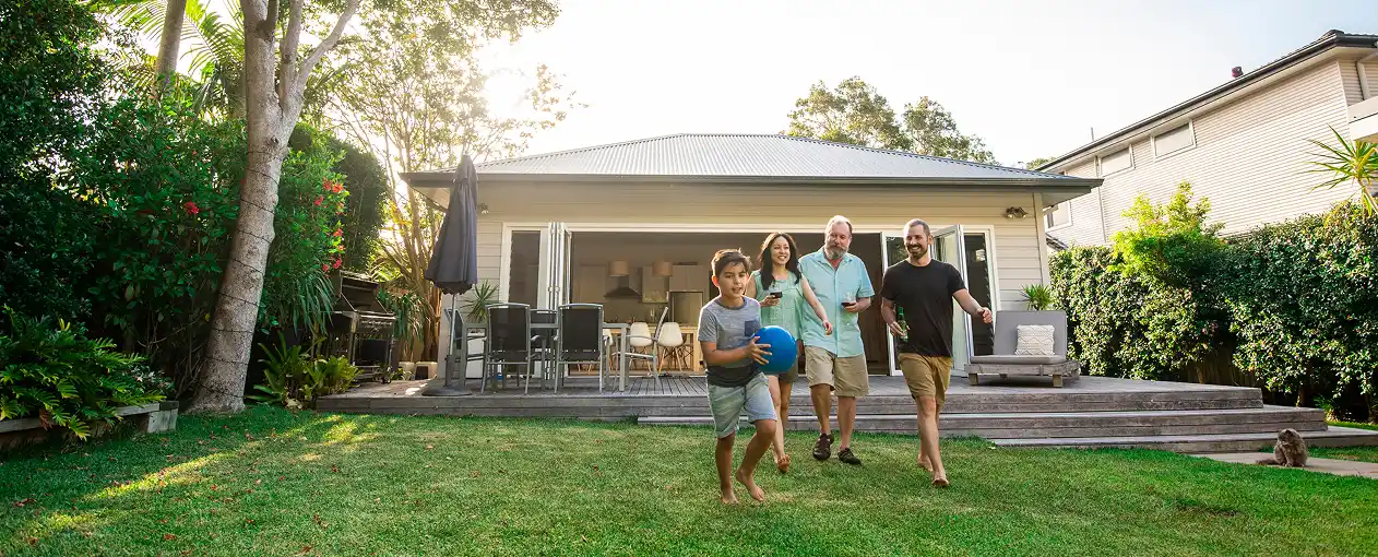 Family of three and their grandfather playing in the backyard with the house on the background